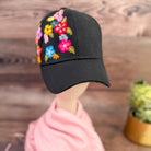Black cap with colorful floral hand embroidery on a wooden surface 