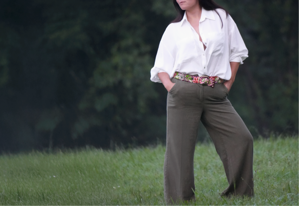 Woman standing in a grassy field wearing a floral embroidered belt